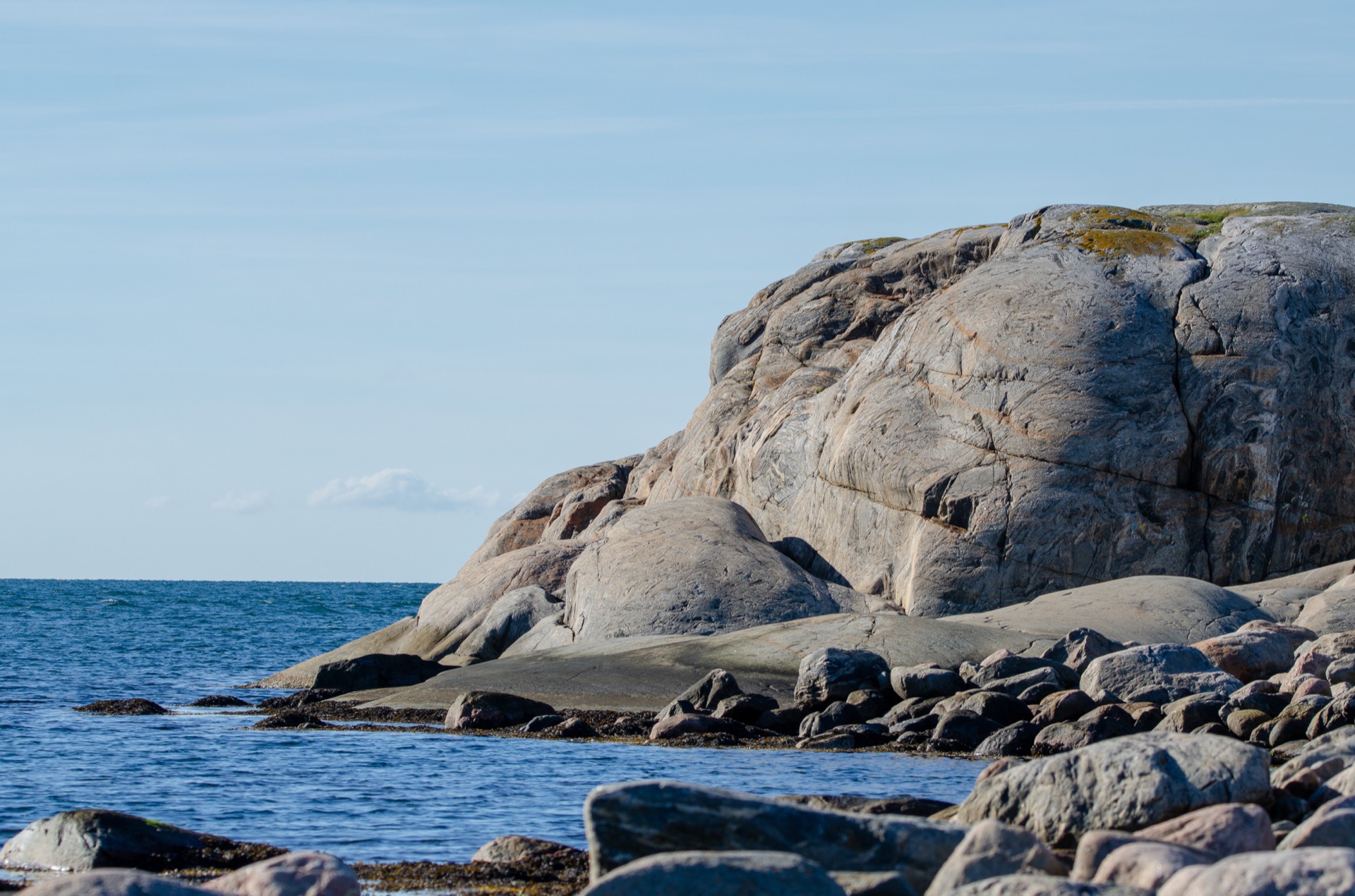 Släta granitklippor vid blått hav i en svensk skärgård en solig dag